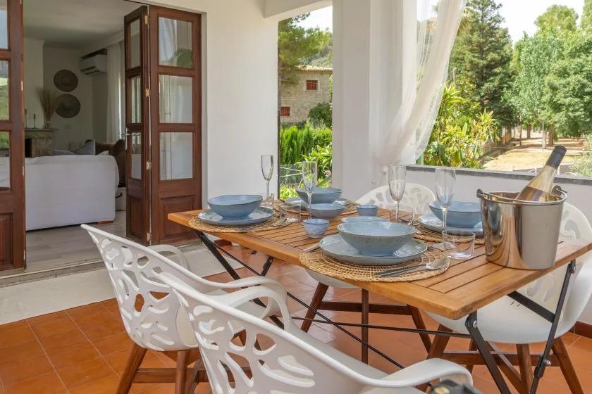 A dining area with a wooden table set with dishes beside an open doorway.