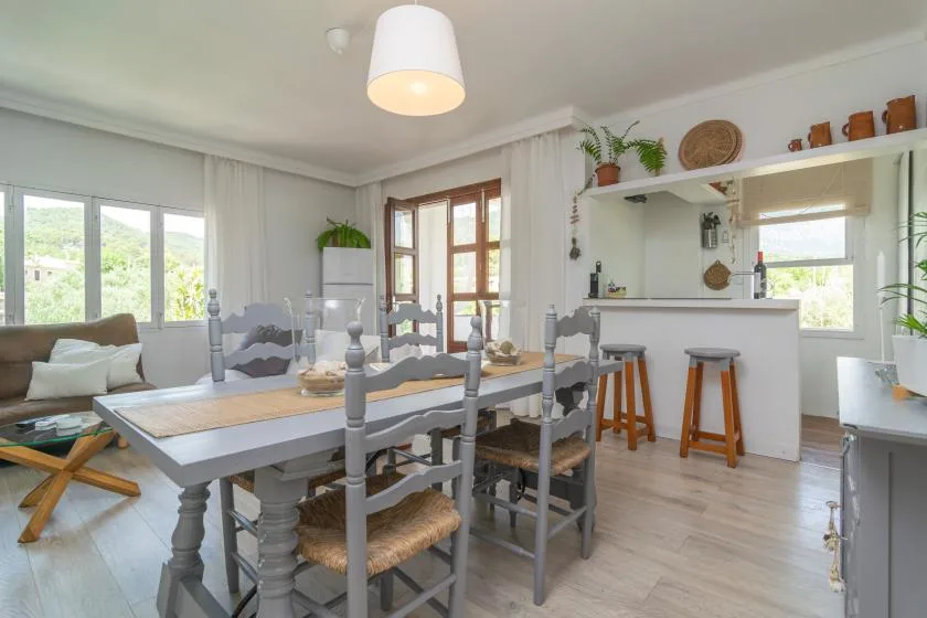 A bright dining area with a long table and a kitchen counter.
