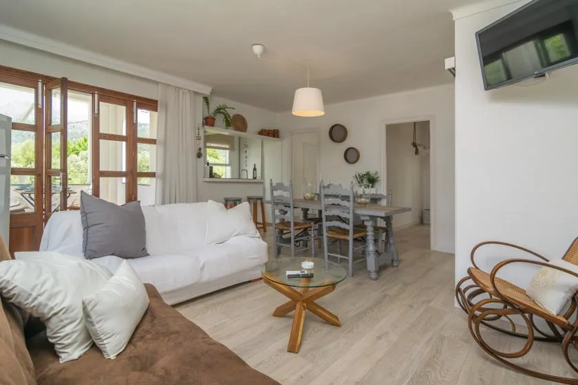 A bright living and dining area with seating, a glass coffee table, and a dining table.