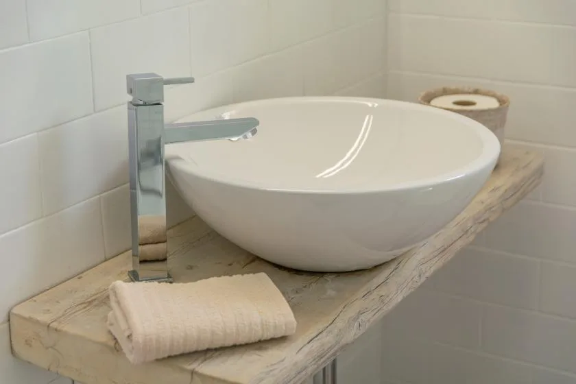 A bathroom vanity with a white vessel sink and folded towel.
