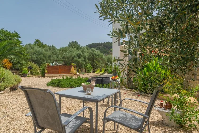 An outdoor patio with a table and seating overlooks a landscaped garden.