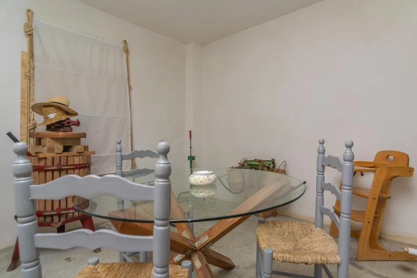 A dining area with a glass table, woven seats, and a wooden high chair.
