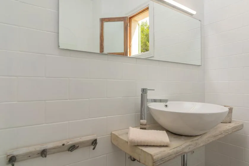 A bathroom vanity with a vessel sink sits beneath a wide mirror.