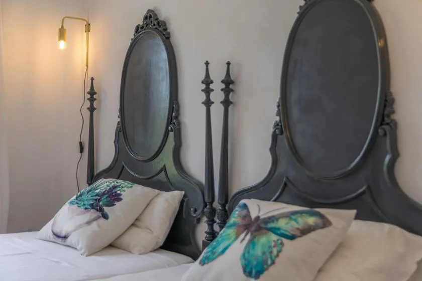 A bedroom with dark ornate headboards and colorful butterfly-patterned pillows.
