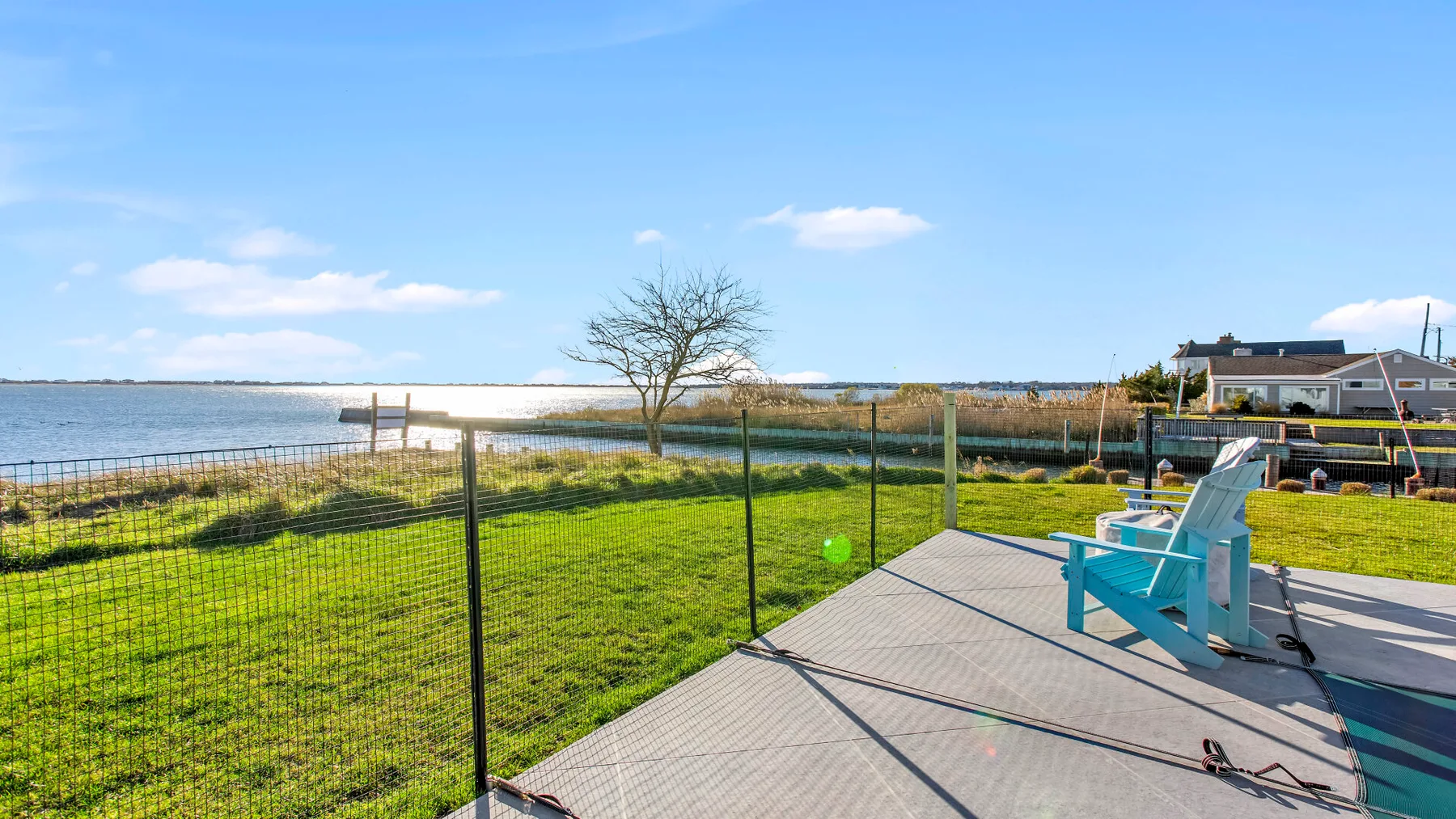 A waterside deck with turquoise seating overlooks a grassy shoreline.
