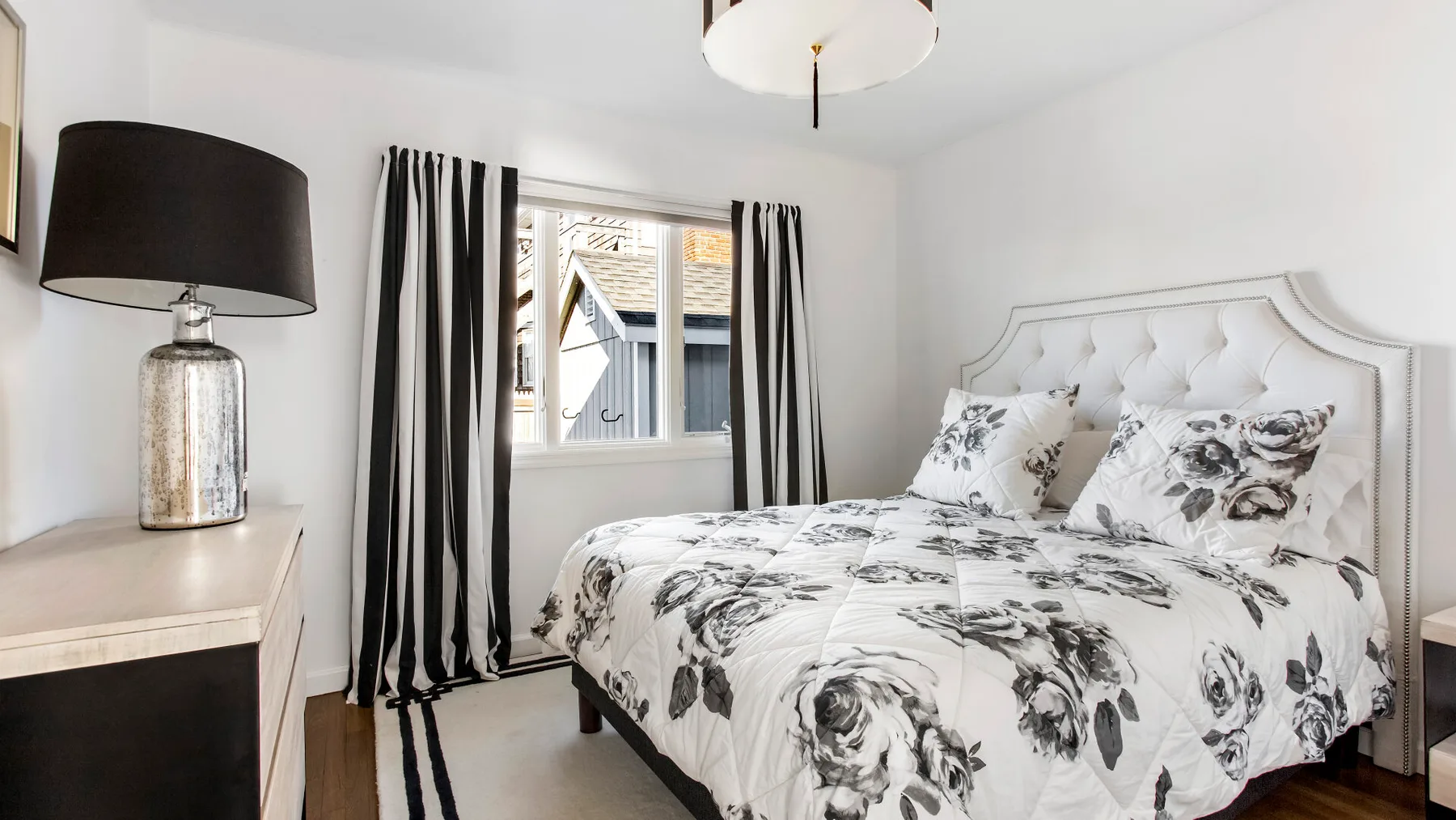 A bedroom with floral bedding and striped curtains beside the window.