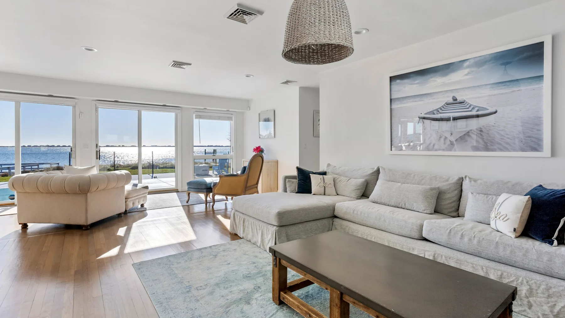 A bright living room with a sectional sofa and large windows overlooking the water.