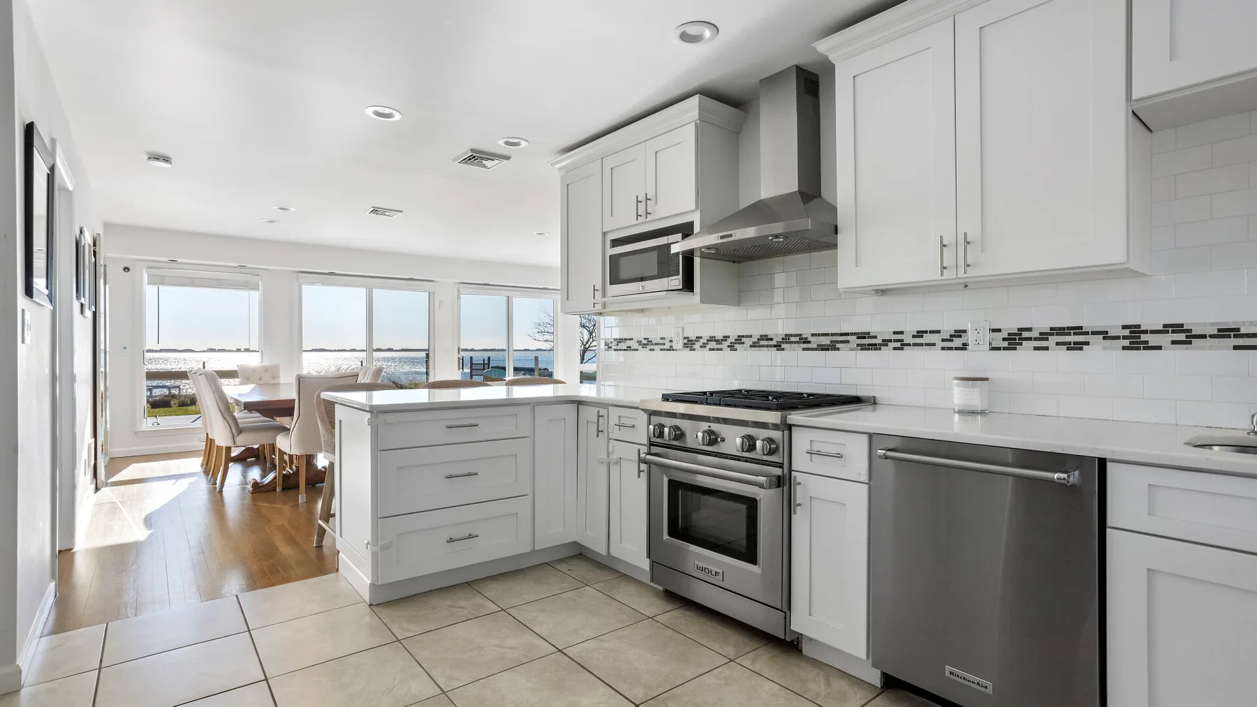 A bright kitchen with white cabinets, a central island, and large windows.