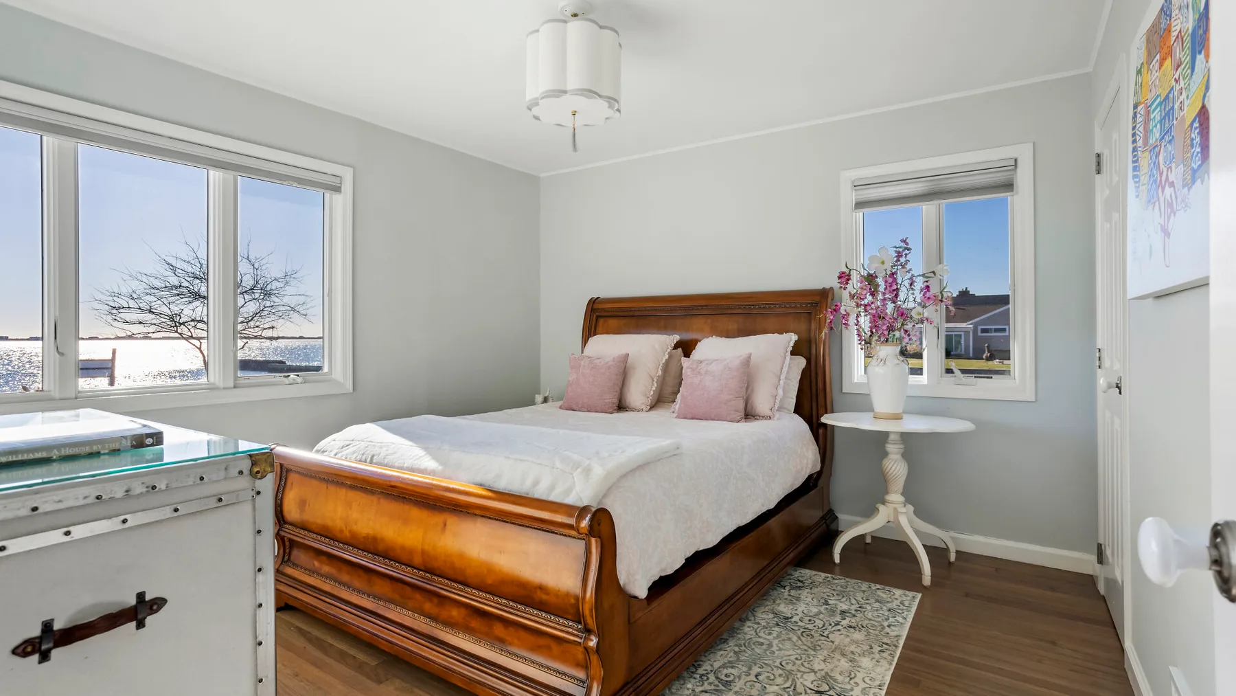 A bedroom with a wooden bed, white bedding, and a bedside table.