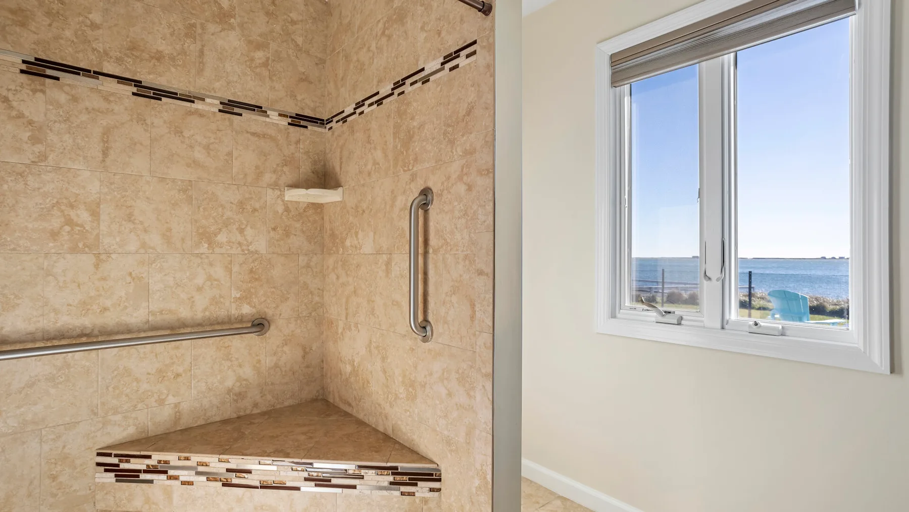 A tiled shower area beside a window overlooking the sea.