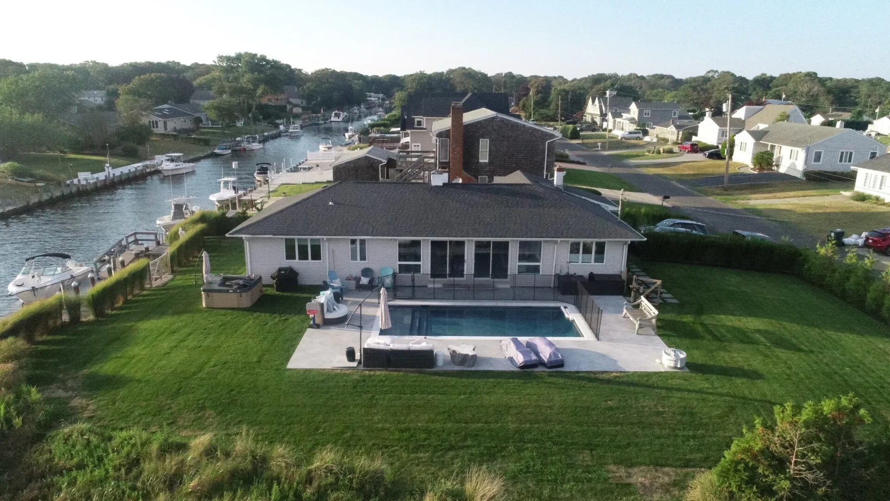Aerial view of a waterfront house with a swimming pool and canal nearby.