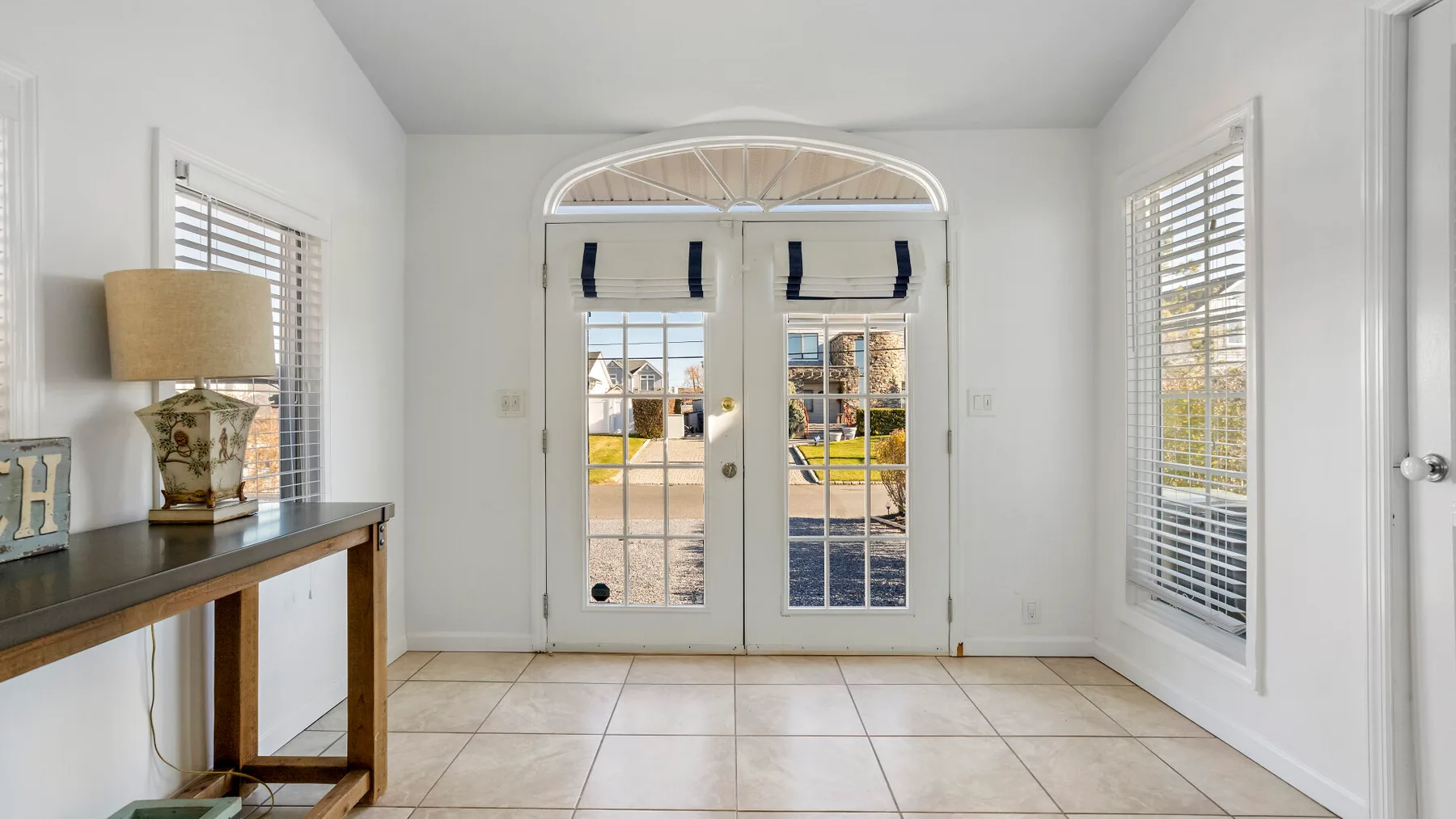 A bright entryway with glass double doors and tiled flooring.