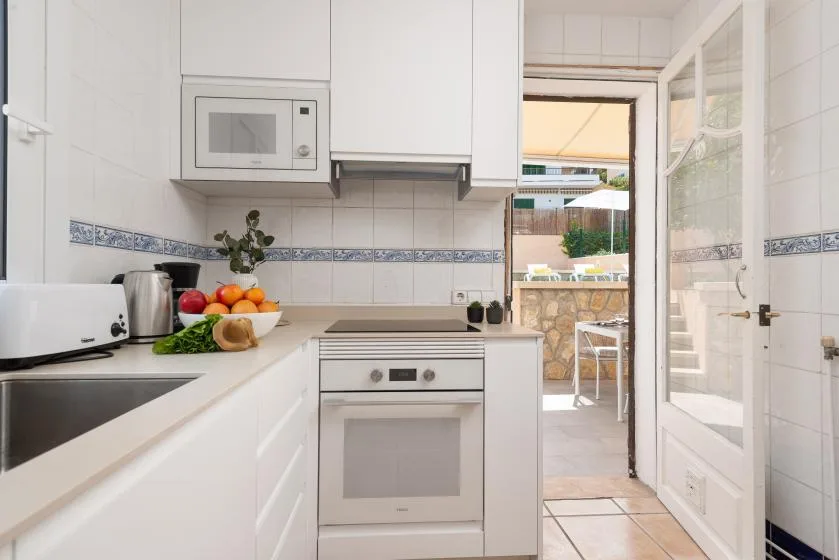 A bright kitchen with white cabinetry, an oven, and a counter opening onto a patio.