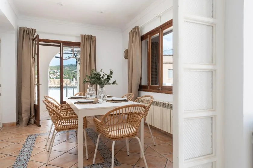 A dining area with a table and chairs beside large windows.