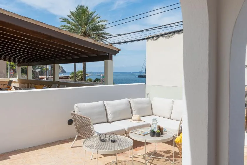 A bright outdoor patio with white seating and a view of the sea.