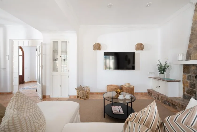 A bright living room features a wall-mounted television and a round coffee table.