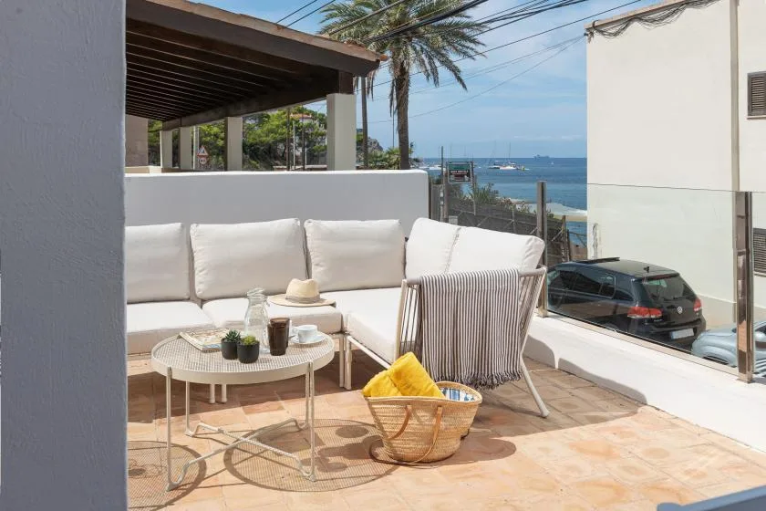 An outdoor lounge area with cushioned seating and a view of the sea.