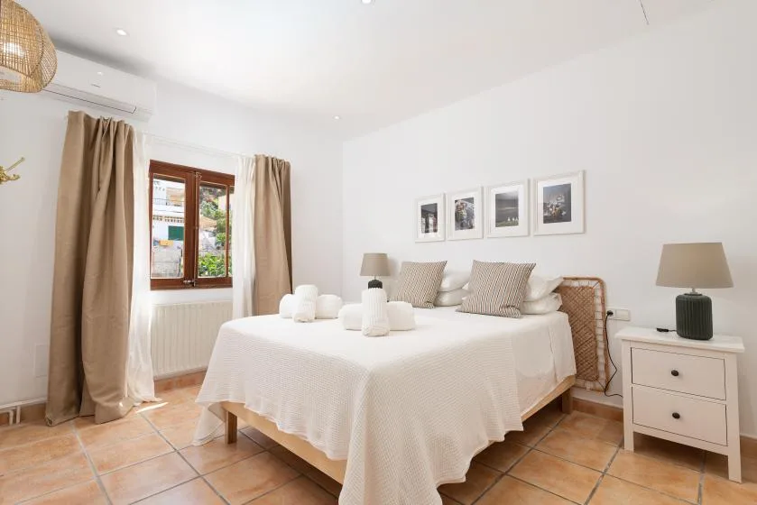 A bright bedroom with a neatly made bed and framed pictures above it.
