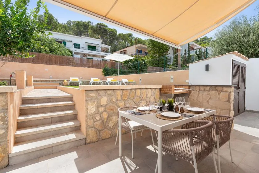 An outdoor dining terrace sits beneath a large awning, with steps leading to an upper patio.