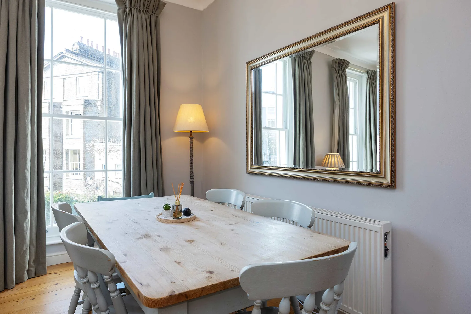 Comedor con una mesa larga de madera junto a una ventana alta.