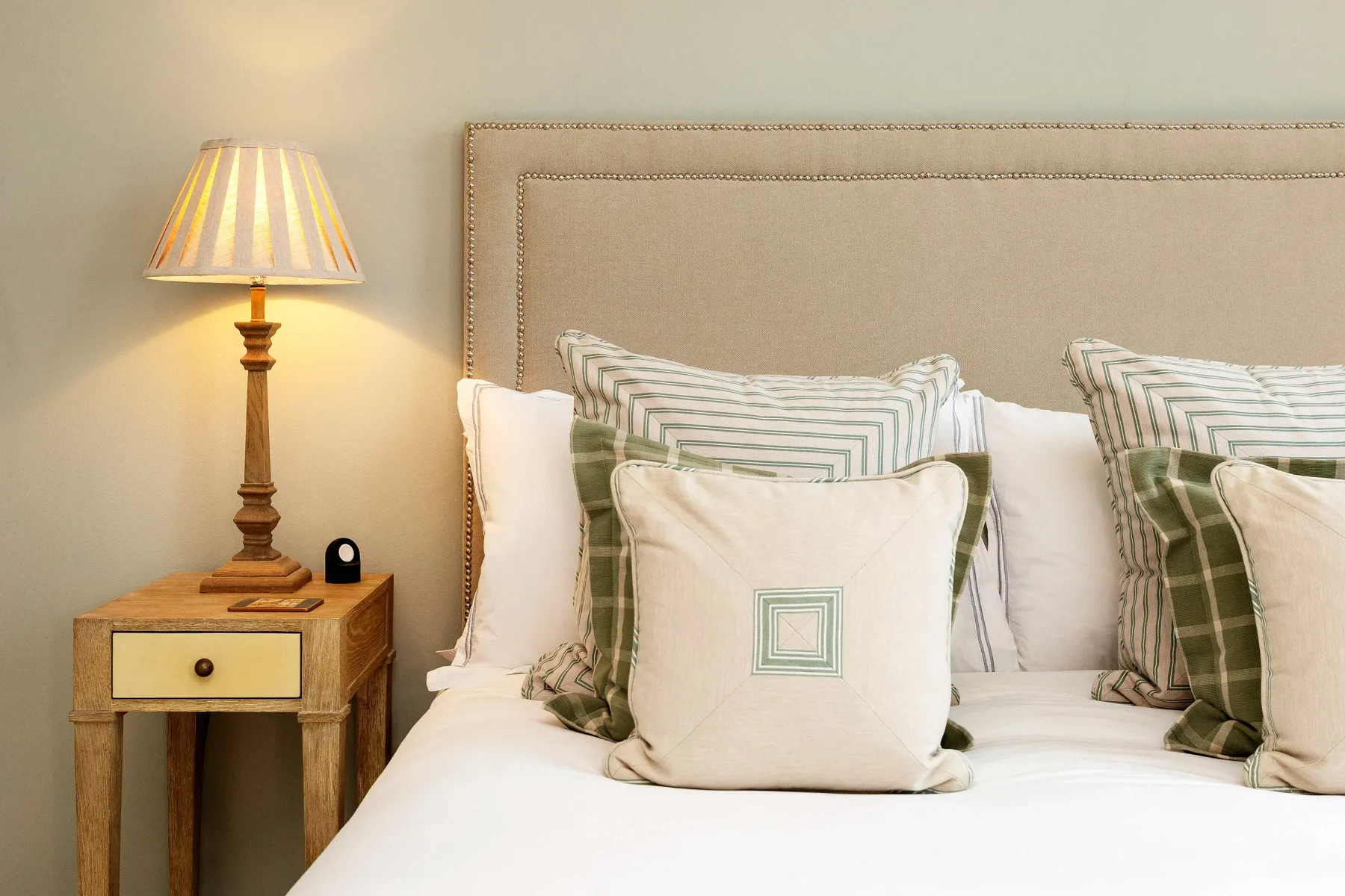 Un dormitorio con una cama tendida y cojines decorativos superpuestos.
