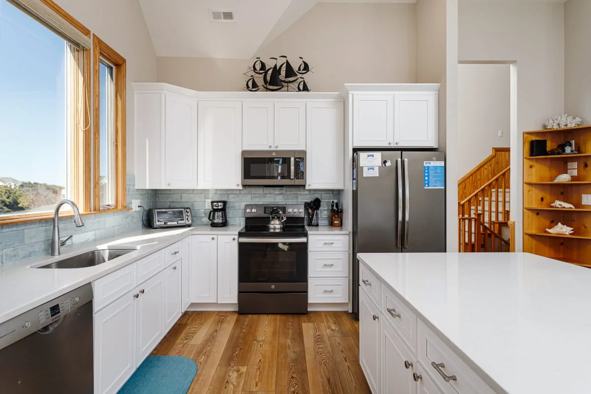 A bright kitchen with white cabinetry, stainless steel appliances, and a large island.