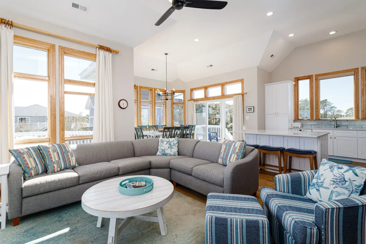 A bright living room with sectional seating and large windows.