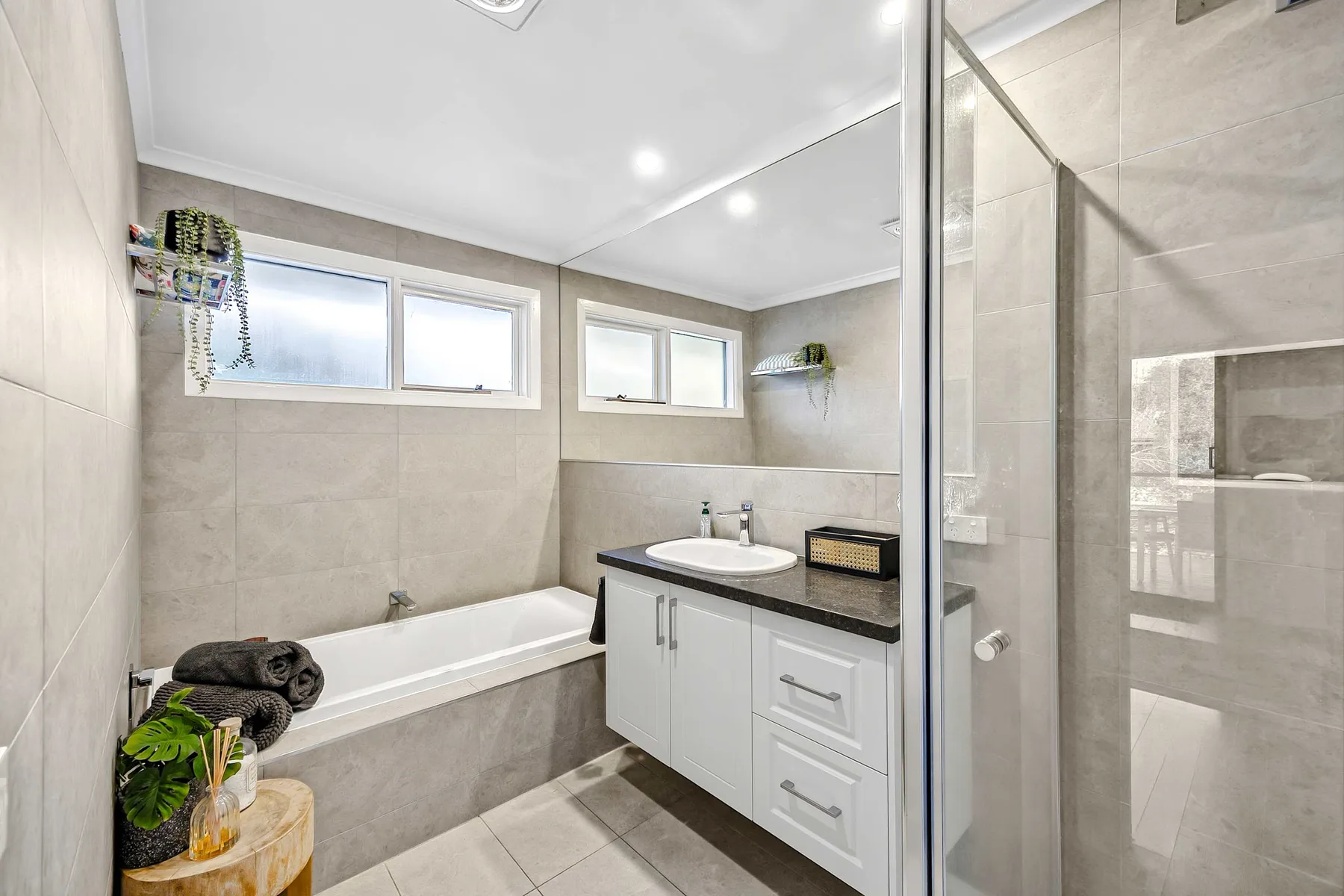A bright bathroom with a bathtub, vanity, and glass shower.