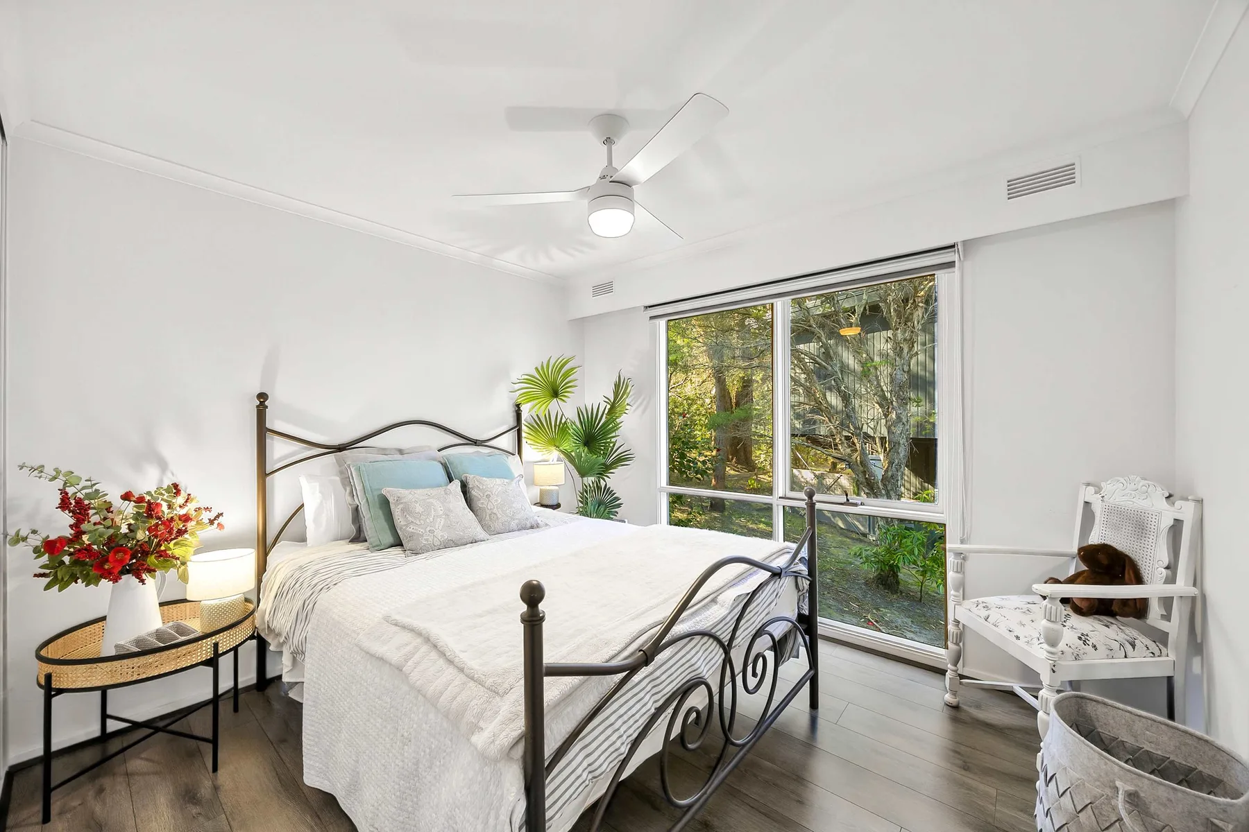 A bright bedroom with a large window and a bed.