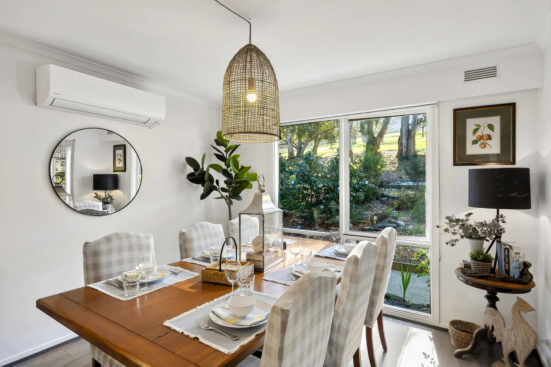 A bright dining area with a set table beside large garden-facing windows.