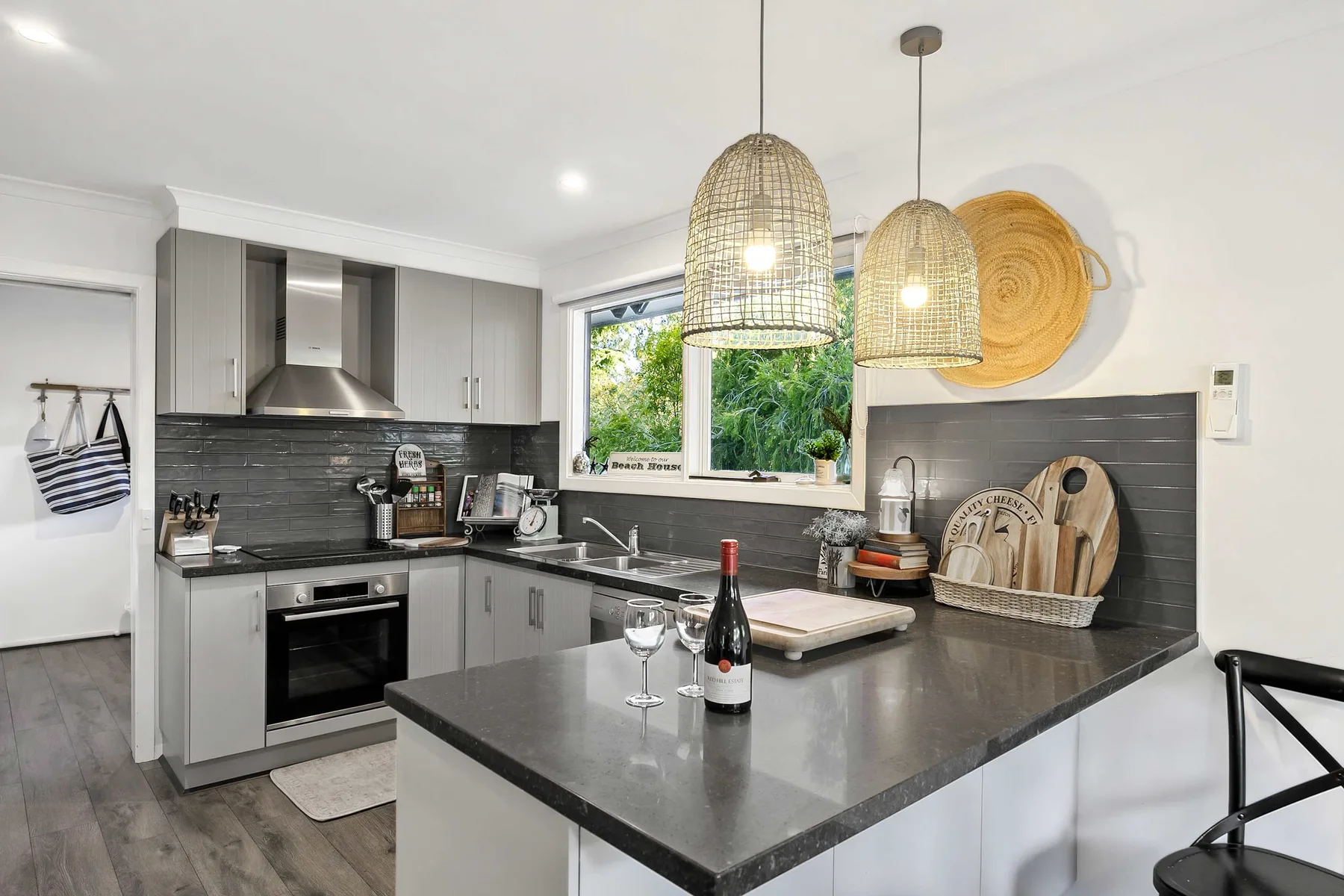 A modern kitchen with a dark island and hanging lights.