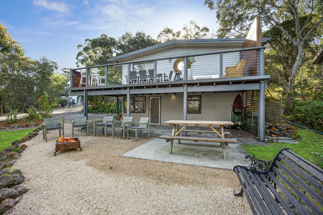 An outdoor seating area beside a raised building, with a picnic table and fire pit.