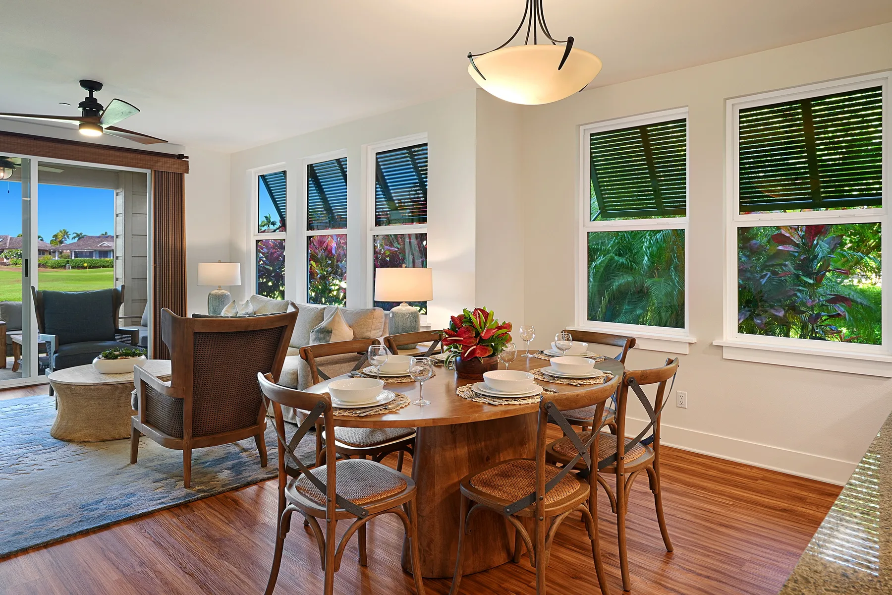 Comedor con una mesa de madera puesta junto a grandes ventanas.
