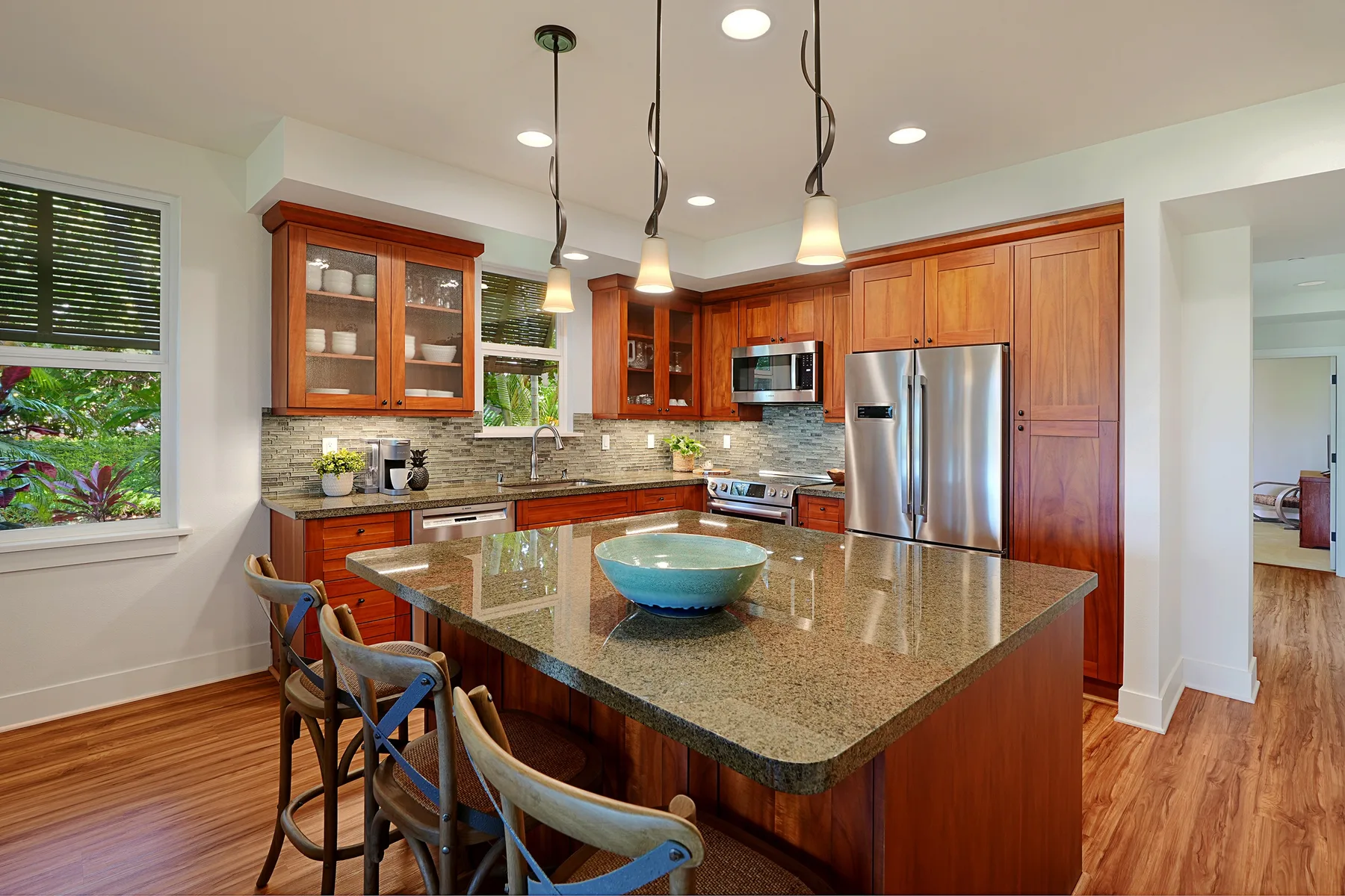 Una cocina luminosa con una isla grande, gabinetes de madera y electrodomésticos de acero inoxidable.