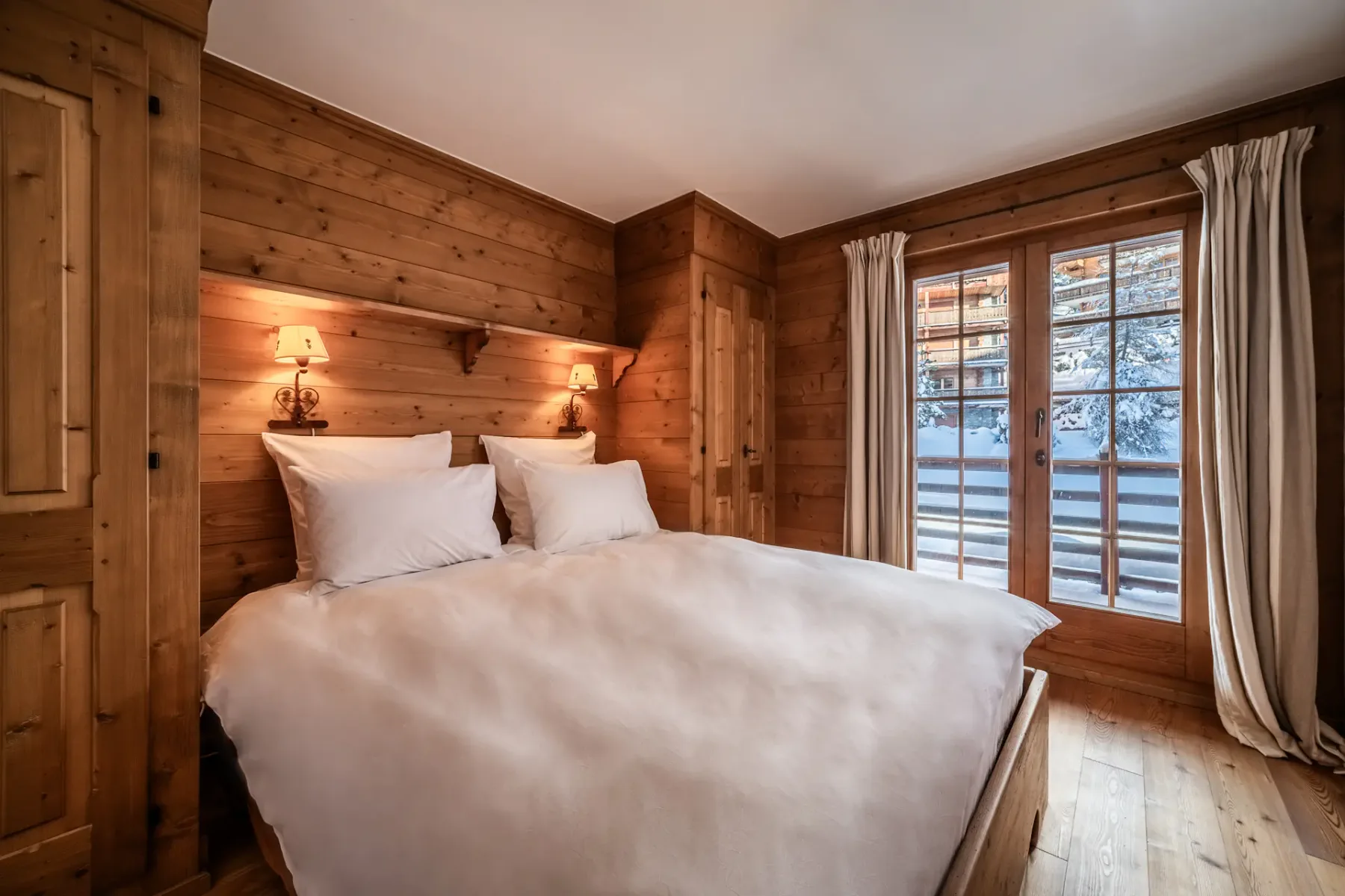 A wooden bedroom with a bed and a balcony.