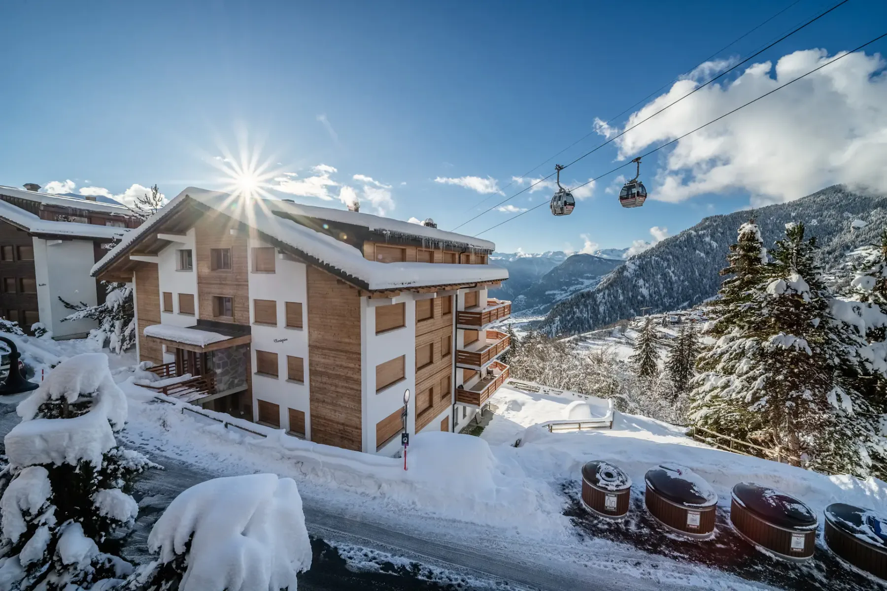 A wooden balcony overlooking snowy mountains and a ski lift.