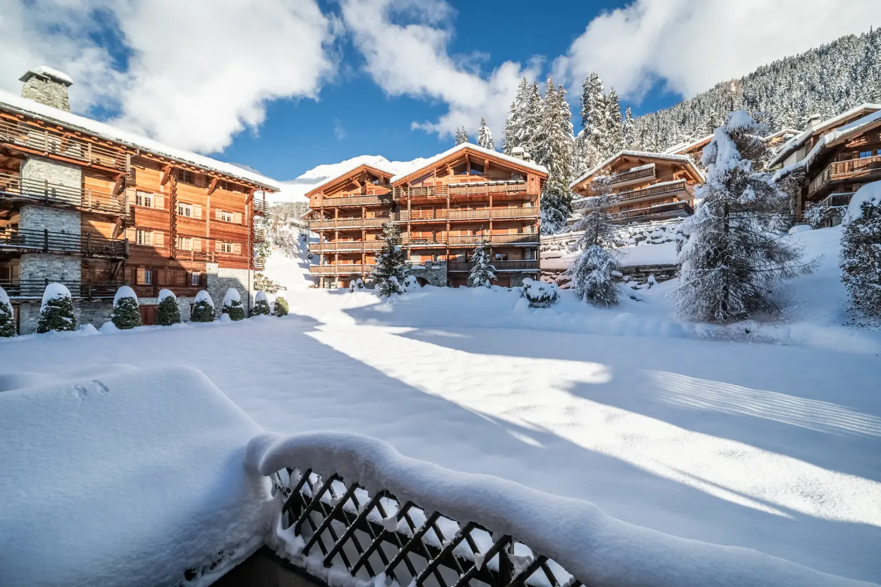 A balcony with snow covered trees and a sun shining on it.