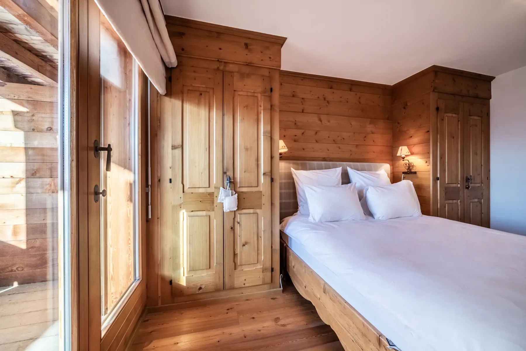 A wooden bedroom with a bed and a balcony.