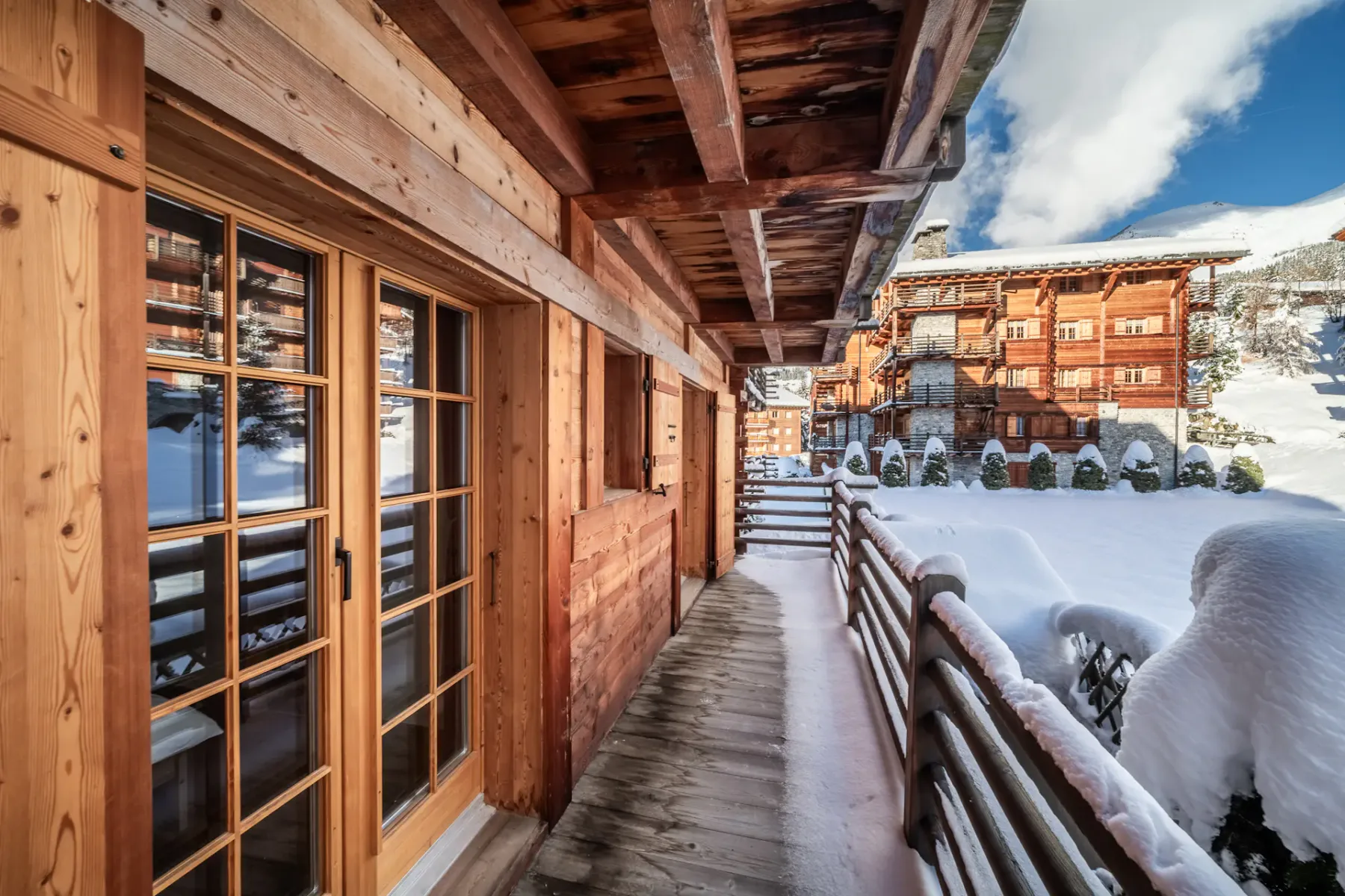 A balcony with snow covered trees and a sun shining on it.