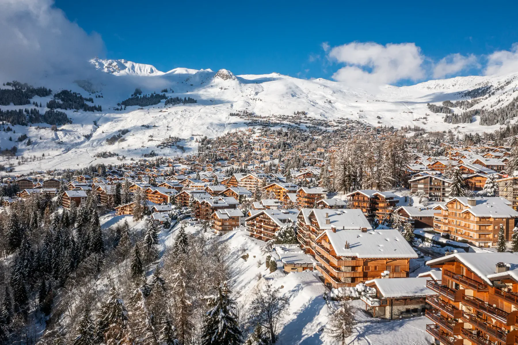 A wooden building covered in snow on a snowy mountainside.