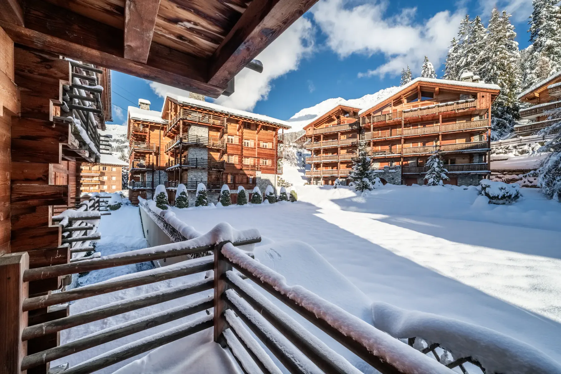 A wooden balcony overlooking snowy mountains and a ski lift.
