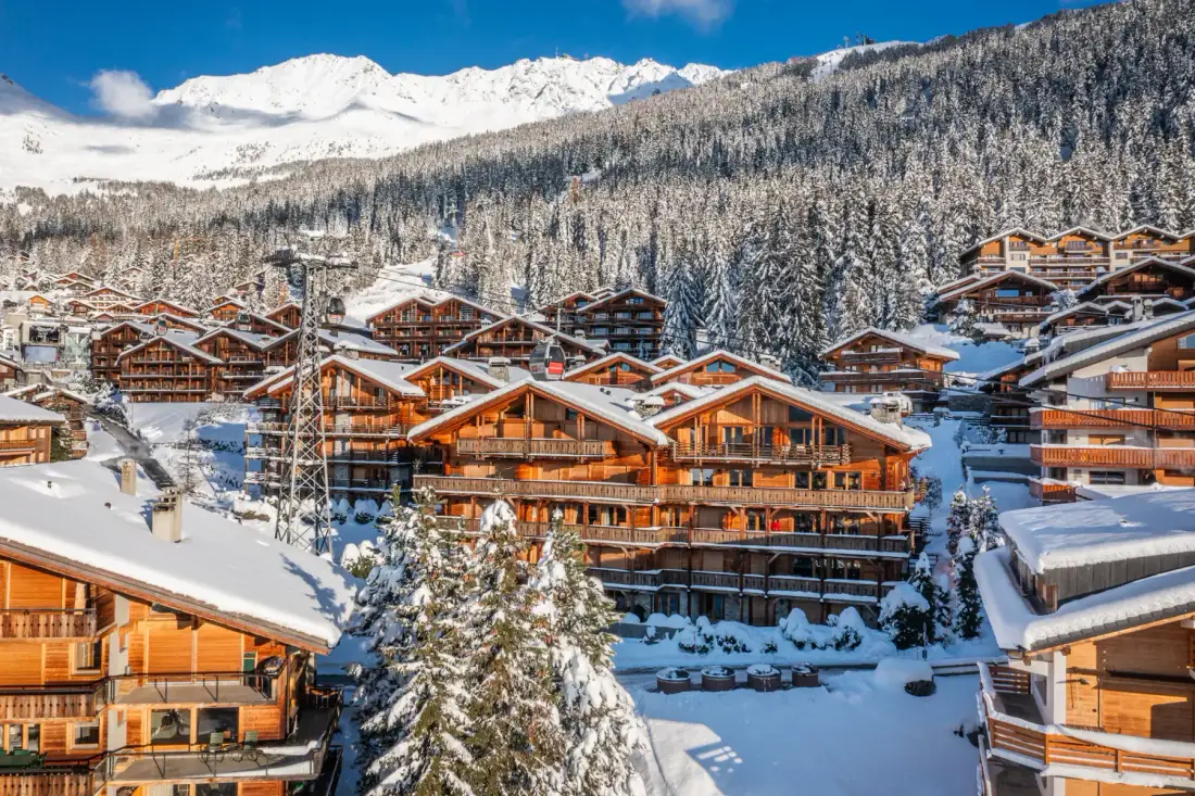 A wooden building covered in snow on a snowy mountainside.