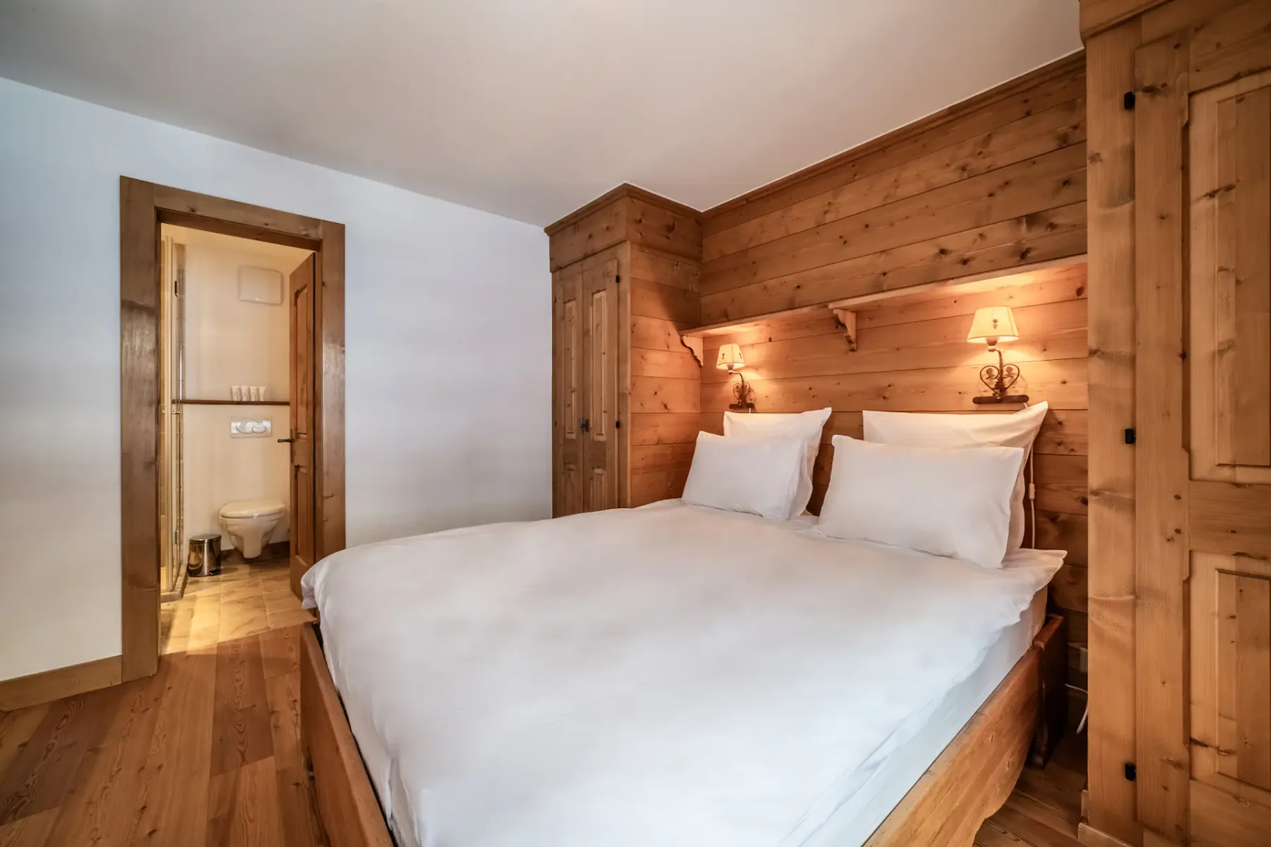 A wooden bedroom with a bed and a balcony.