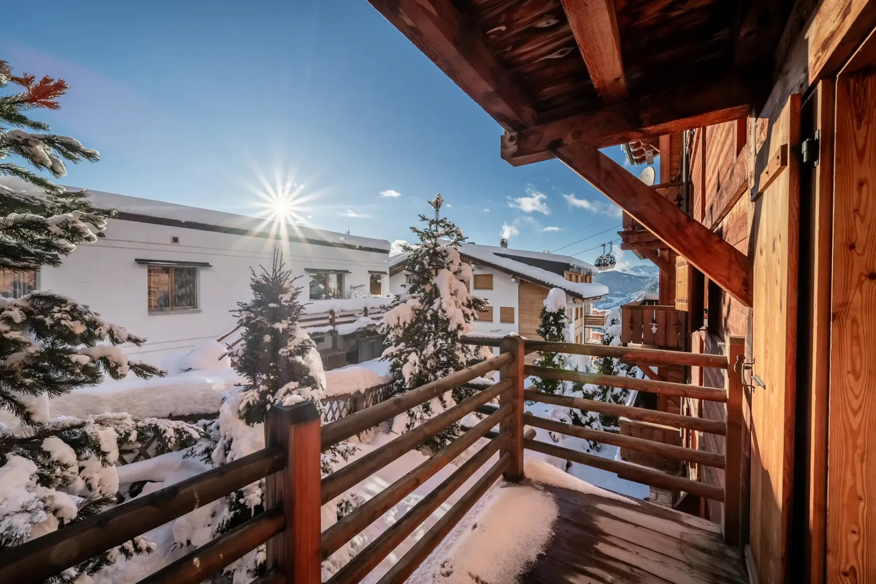 A balcony with snow covered trees and a sun shining on it.