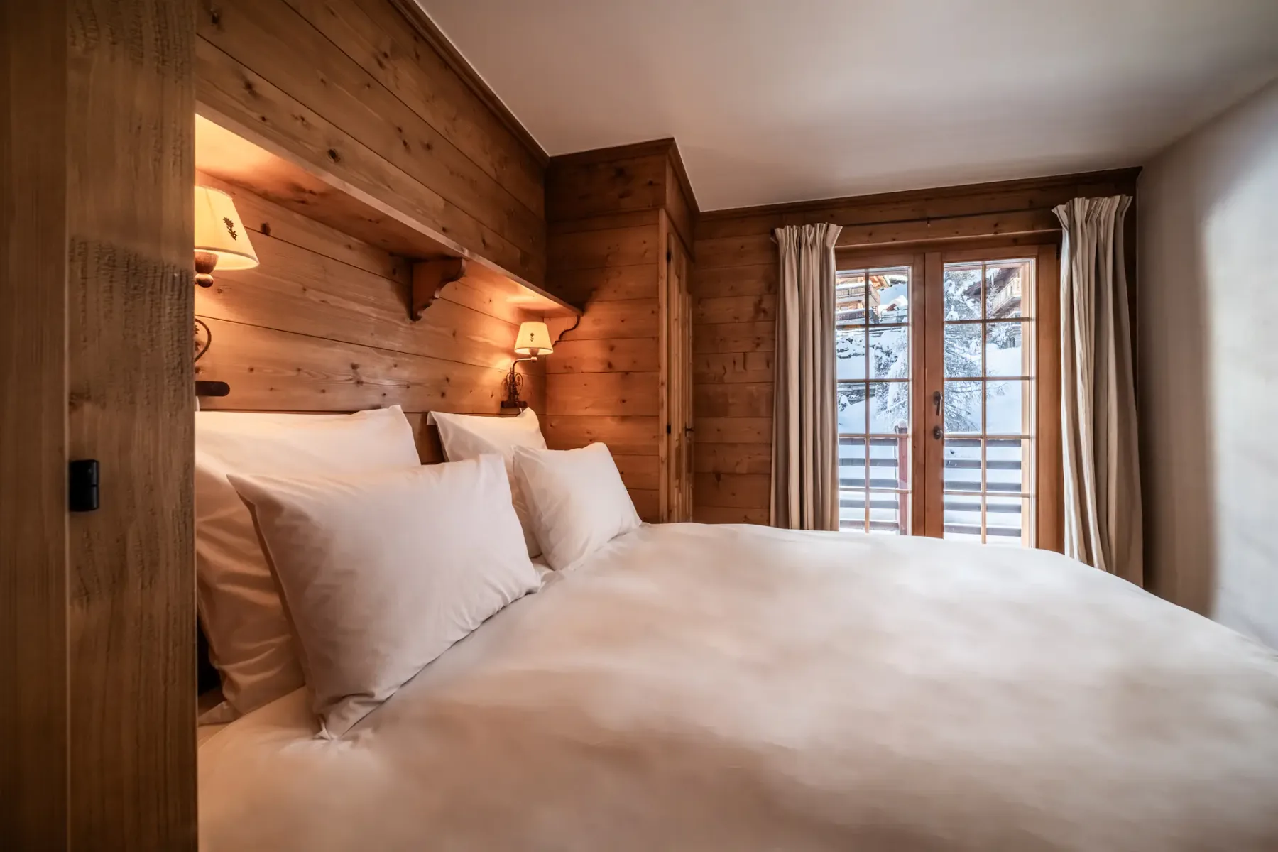 A wooden bedroom with a bed and a balcony.