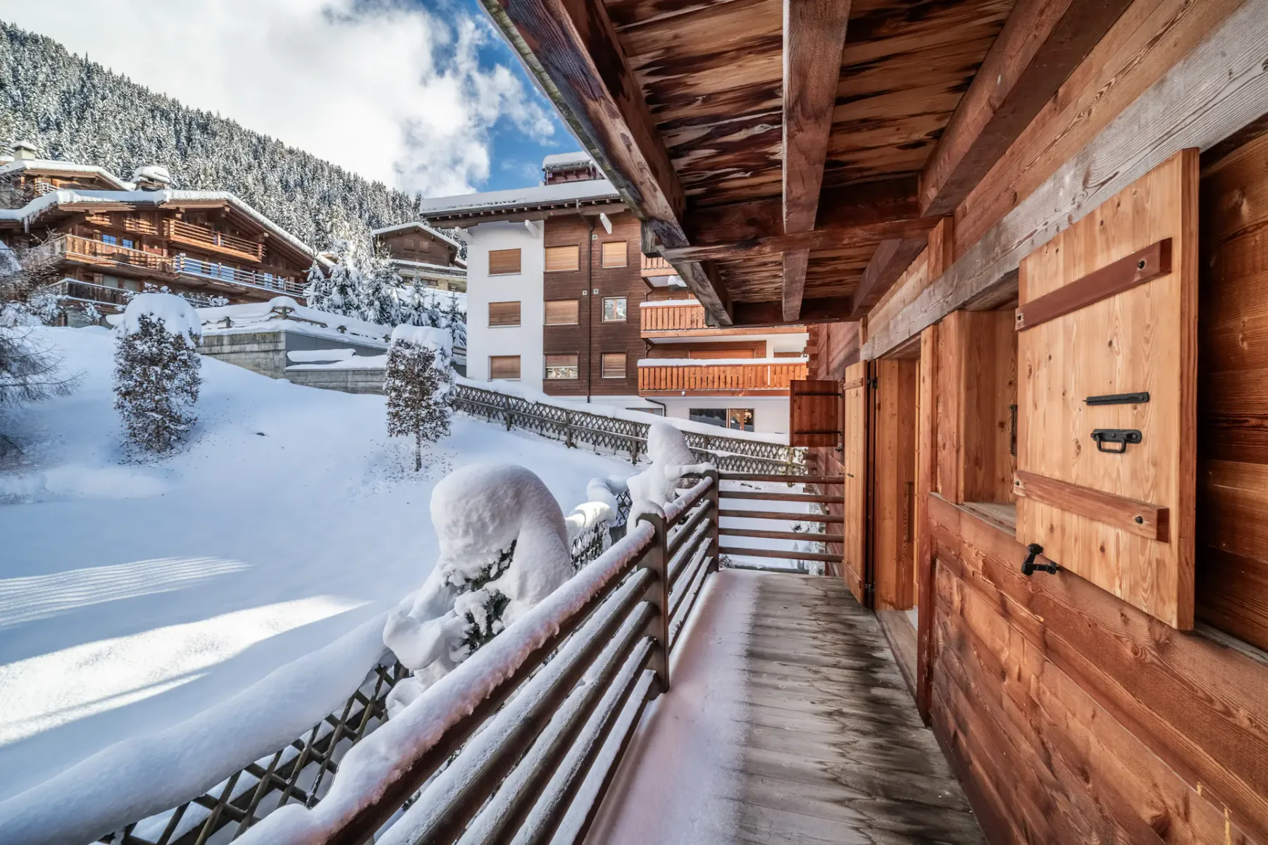 A balcony with snow covered trees and a sun shining on it.