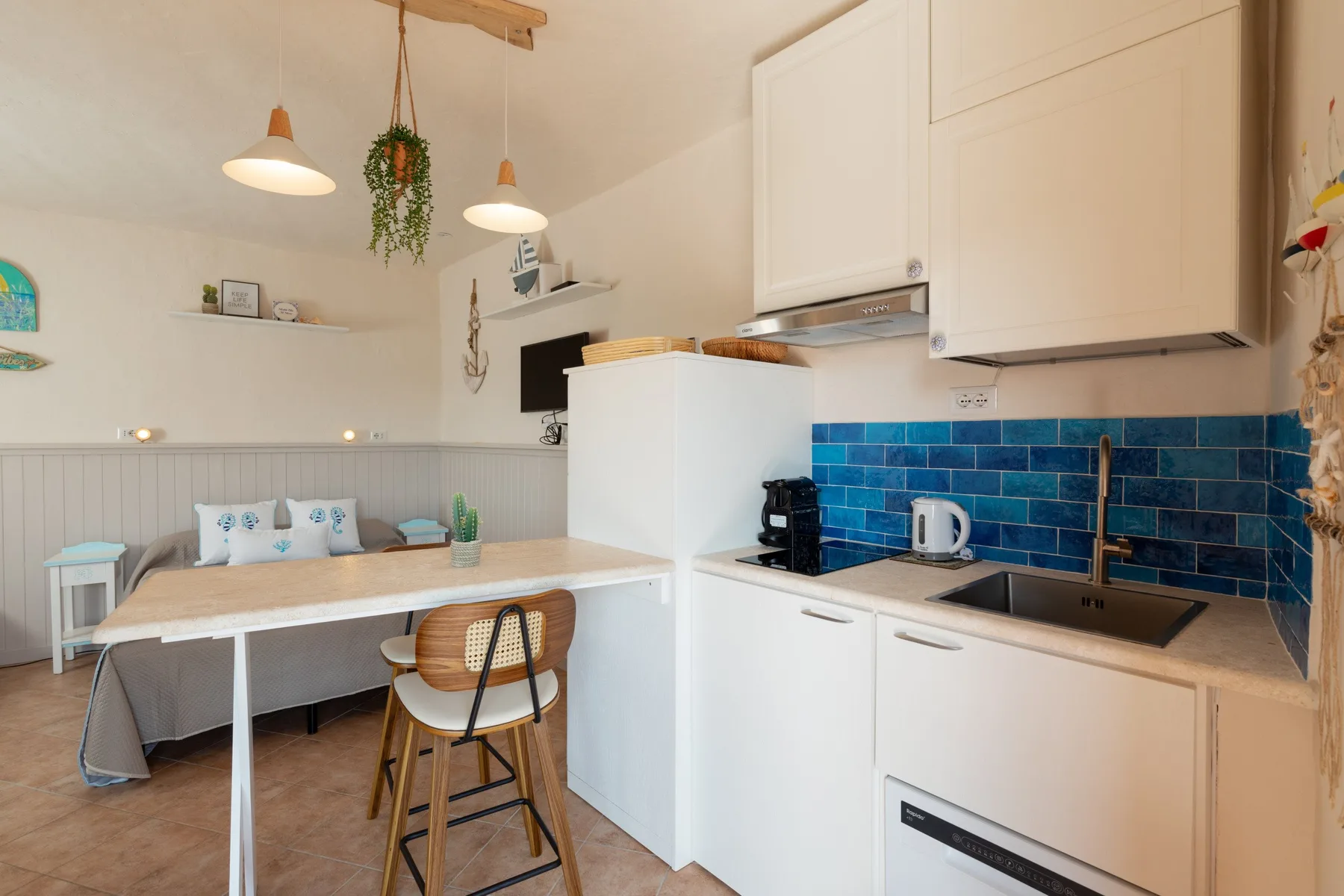 Una cocina y comedor luminosos con armarios blancos y azulejos azules.