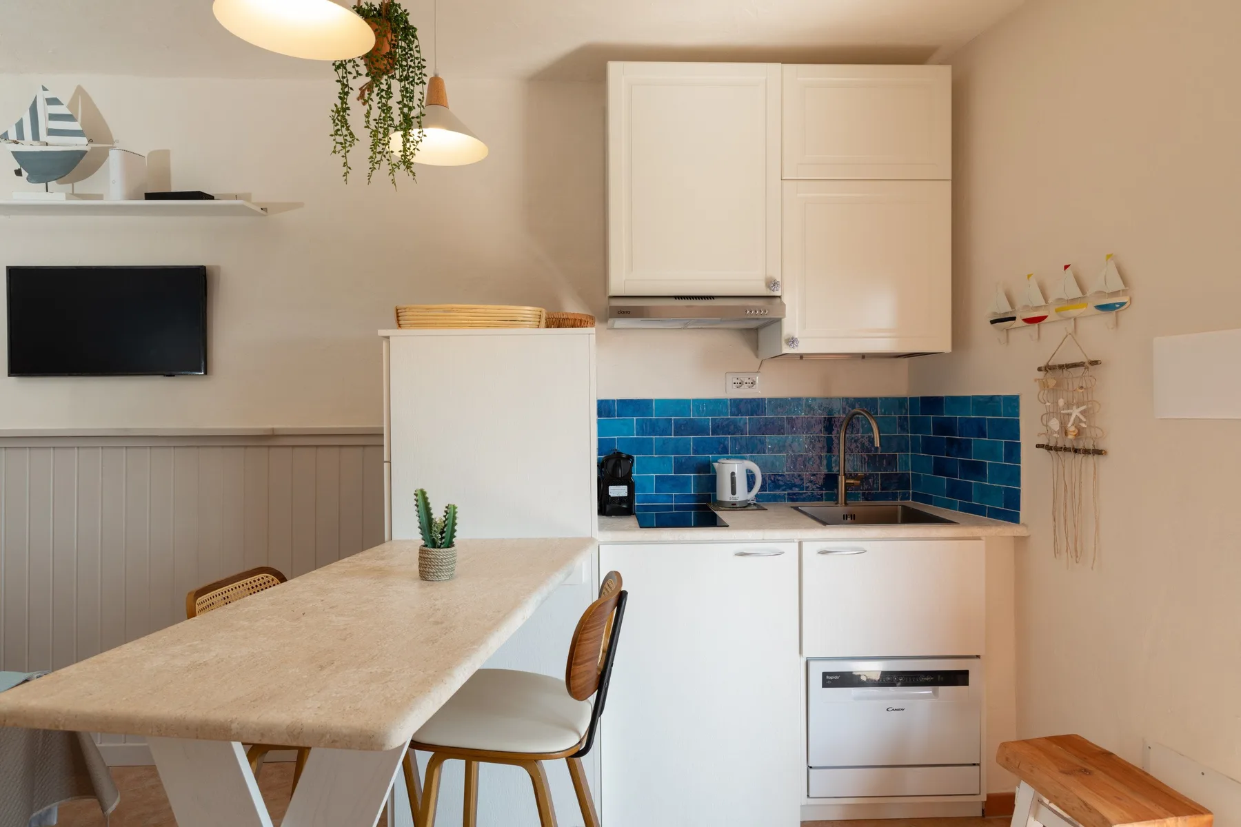 Una pequeña cocina y zona de comedor con azulejos azules y una mesa.