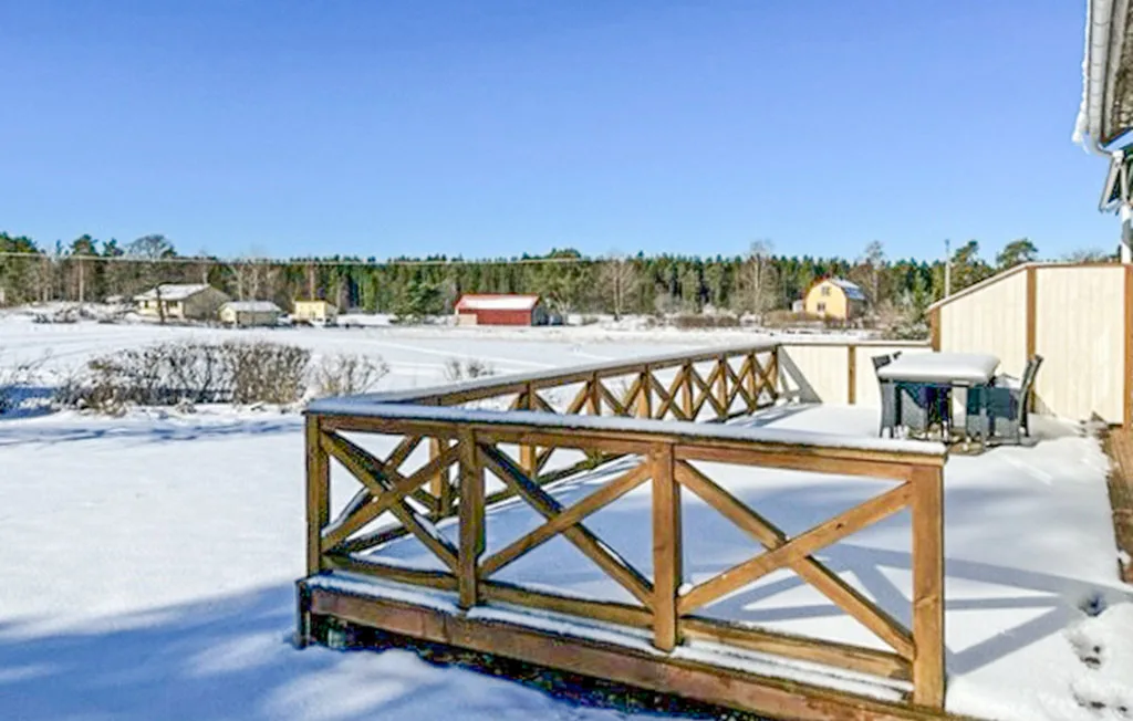 Una barandilla de madera da a una zona exterior cubierta de nieve.