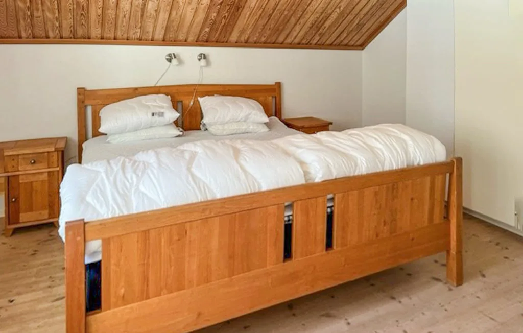 Un dormitorio con una cama de madera vestida con ropa de cama blanca.
